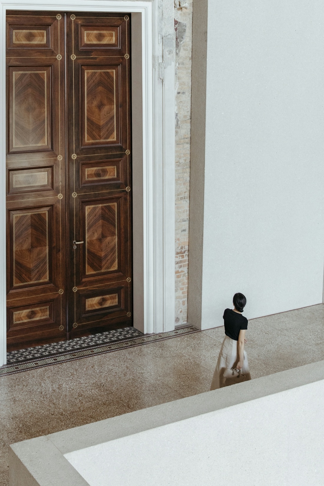 Grand walnut doors in a light-filled gallery hall